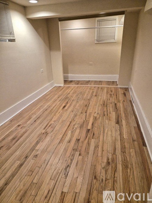 A room with wooden flooring and a window with blinds.