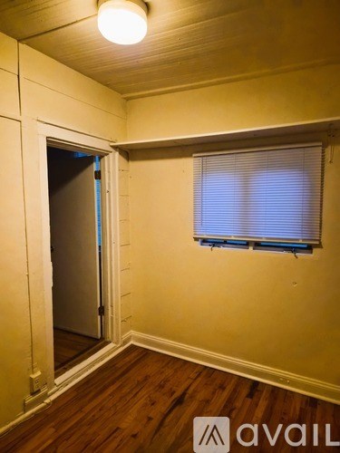 A room with a wooden floor and a window with blinds.