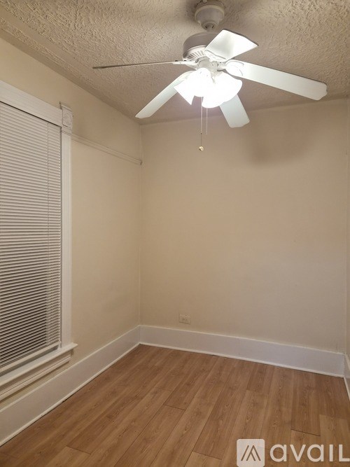 A room with a ceiling fan and wooden flooring.