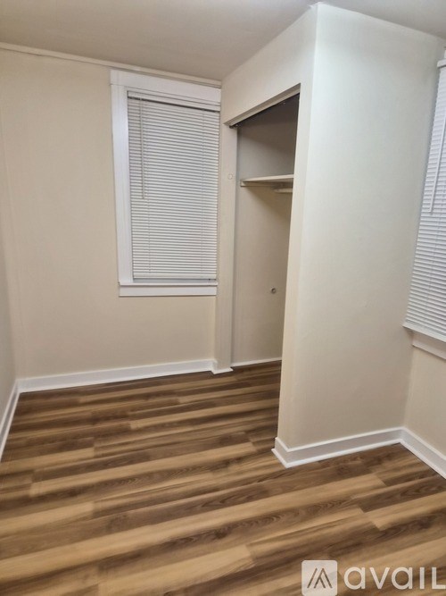 A room with wooden flooring and a window with blinds.