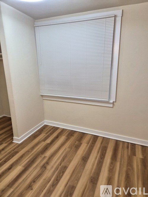 A room with wooden flooring and a window with blinds.