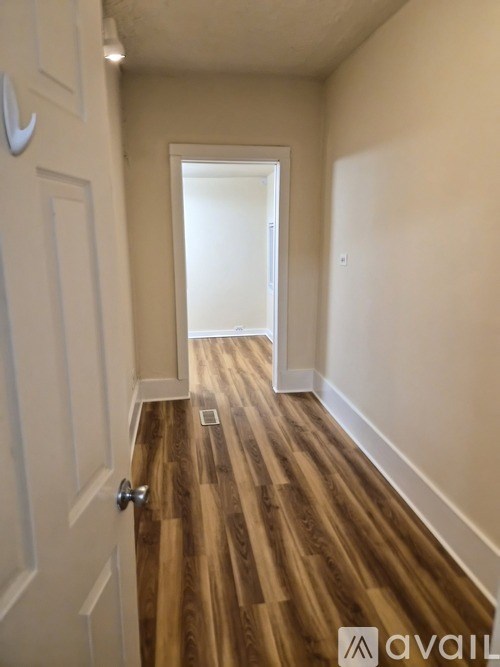 A hallway with a wooden floor and white walls.