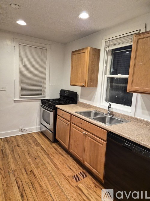 A kitchen with wooden cabinets and a black dishwasher.