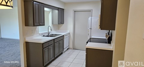 A kitchen with a white counter top and dark brown cabinets.