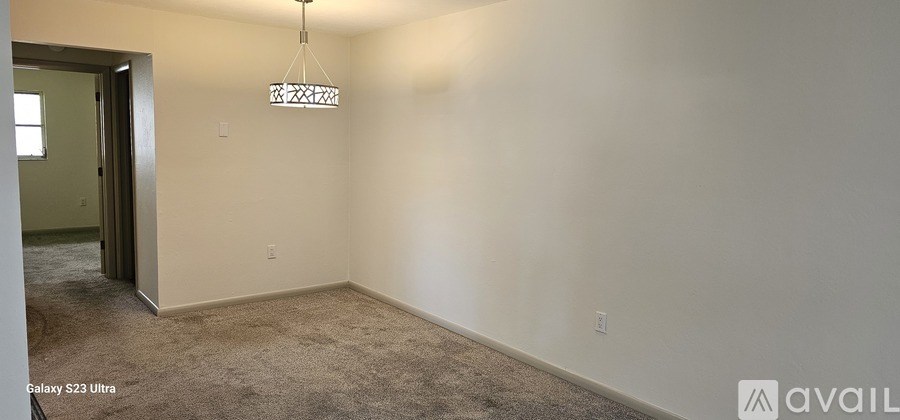 A room with a carpet floor and a chandelier hanging from the ceiling.