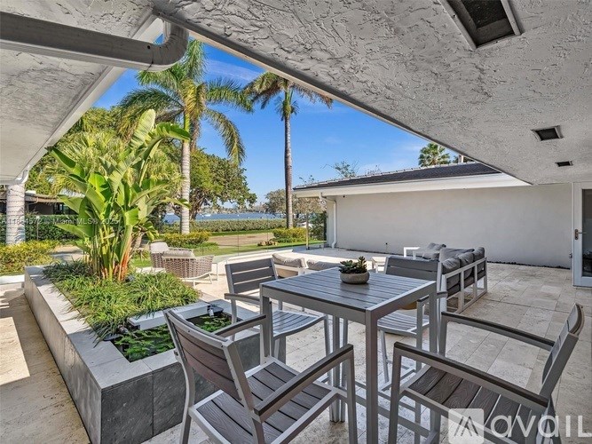 A patio with a table and chairs under a roof.