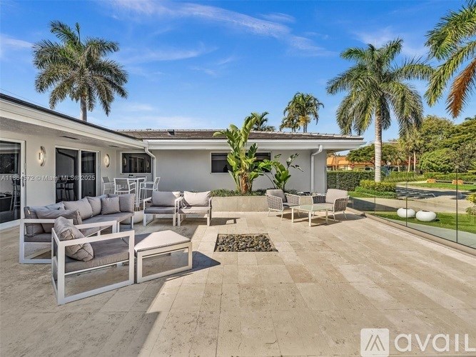 A patio area with furniture and palm trees.
