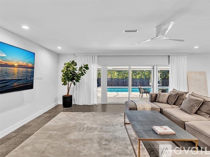 A living room with a large painting on the wall and a view of the outdoors through the sliding glass doors.