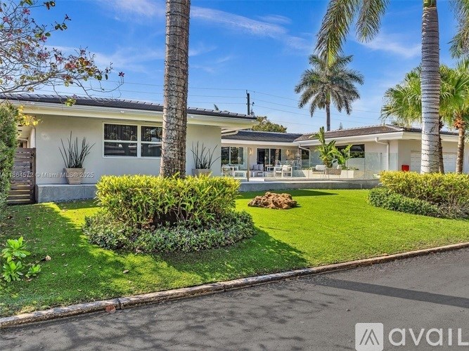 A house with a front yard and palm trees.