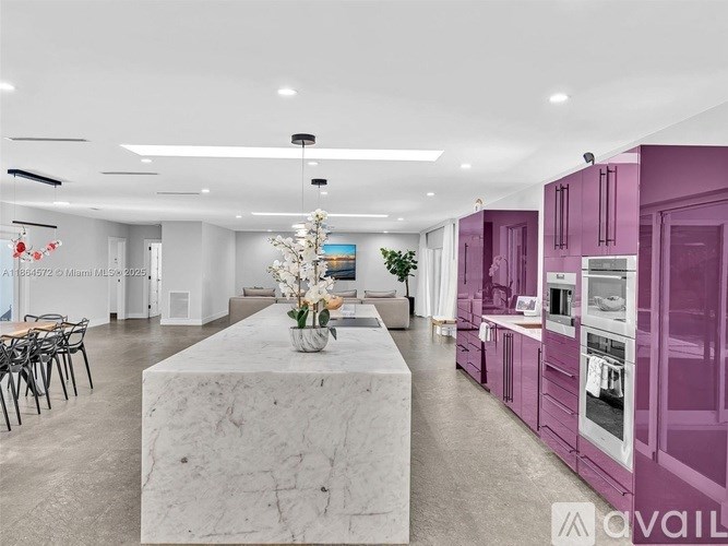 A modern kitchen with purple cabinets and a marble island.