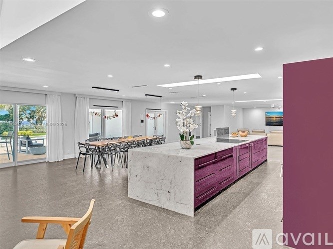 A modern kitchen with a marble island and purple cabinets.
