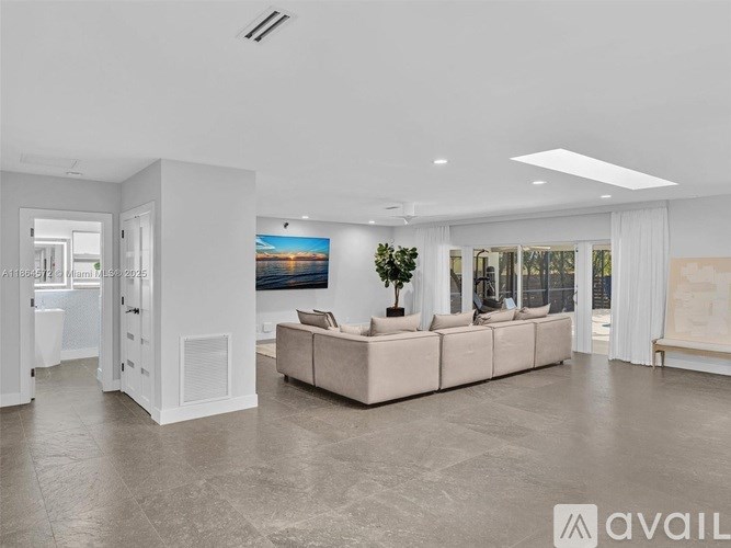 A spacious living room with a large beige sofa and a painting on the wall.