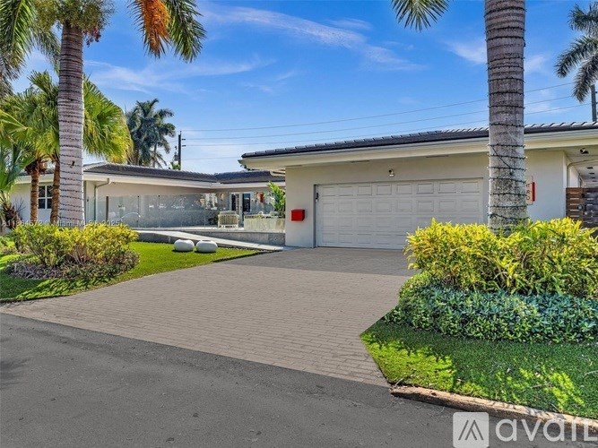 A house with a driveway and palm trees in front.