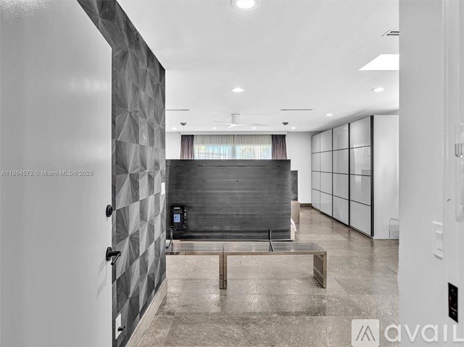 A modern, empty room with a black and white checkered wall and a wooden bench.