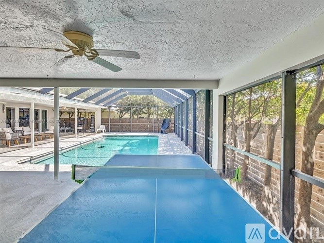 A blue air hockey table is in the middle of a room with a ceiling fan and a pool table.