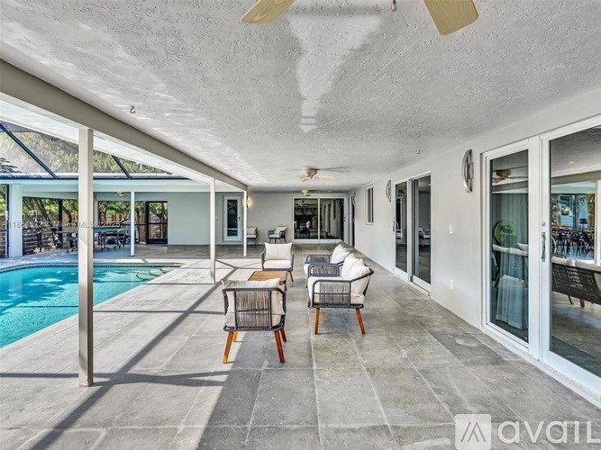 A patio with a pool and chairs.