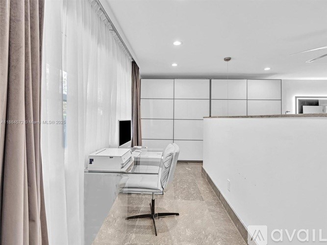 A modern kitchen with a white countertop and a chair.