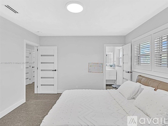 A bedroom with a large bed and a window with blinds.