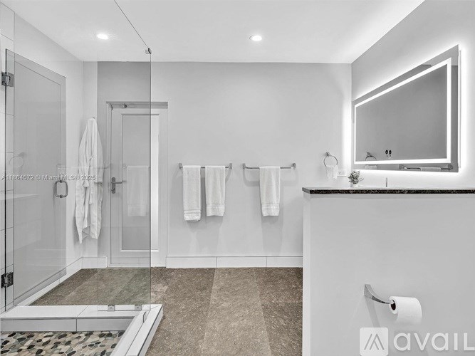 A bathroom with a glass shower door and a marble floor.