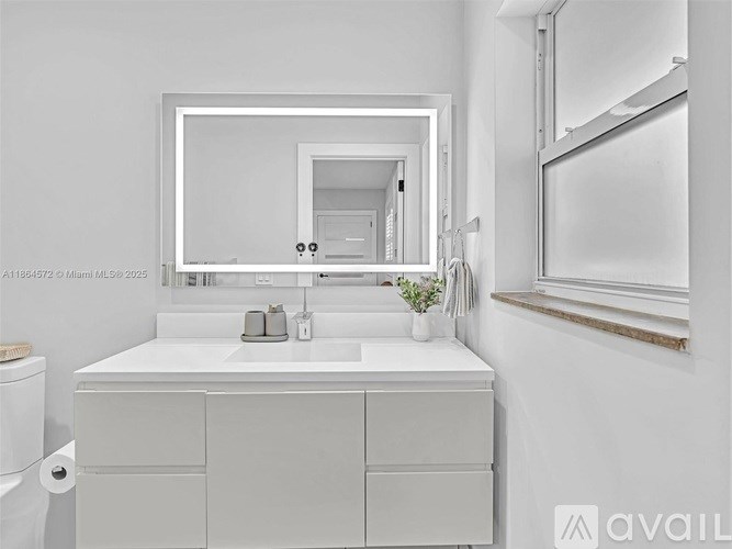 A white bathroom with a sink, mirror, and toilet.