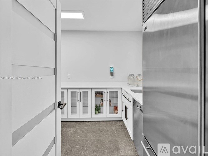 A kitchen with white cabinets and a stainless steel refrigerator.