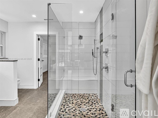 A modern bathroom with a walk-in shower and a tiled floor.