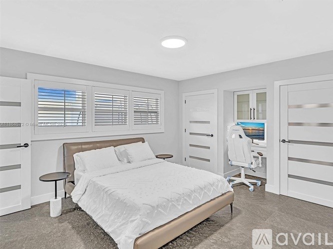 A bedroom with a bed, a chair, and a desk with a computer.