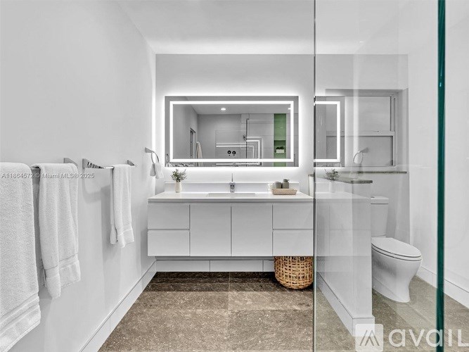 A modern bathroom with a large mirror and white cabinetry.