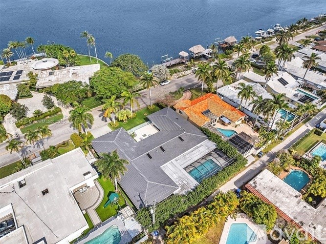 A large house with a swimming pool is surrounded by palm trees.