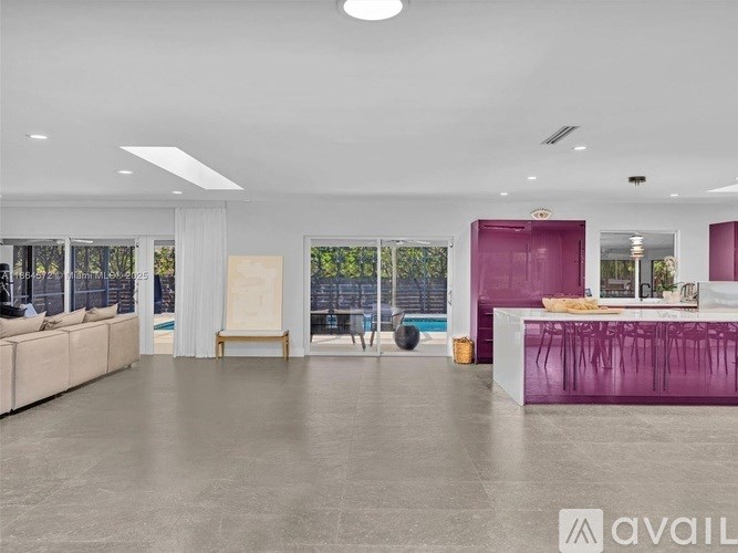 A spacious living room with a purple kitchen area and a white sofa.