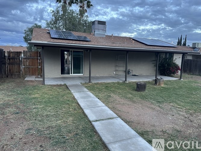 A house with solar panels on the roof and a fence in the backyard.