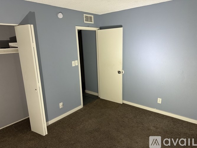 A room with two doors, one open, and a carpeted floor.
