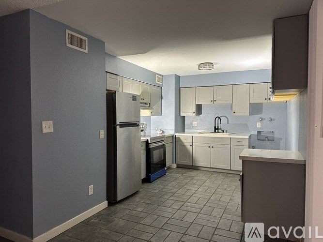 A kitchen with a refrigerator, sink, and cabinets.