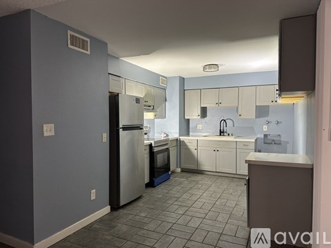 A kitchen with a refrigerator, sink, and cabinets.