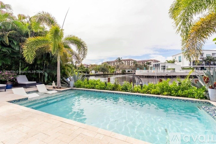 A pool surrounded by palm trees and a building in the background.