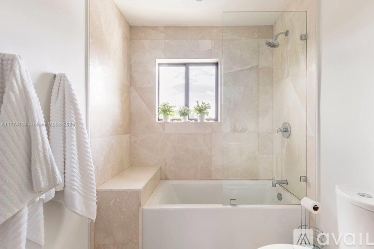 A bathroom with a tub, towel rack, and window.