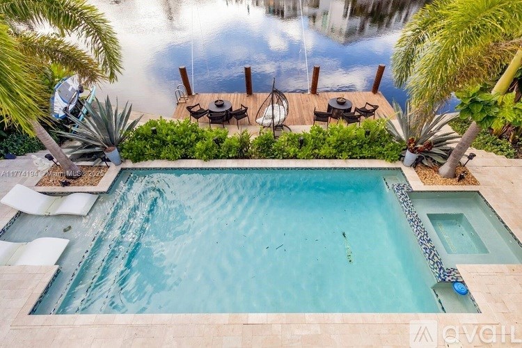 A pool surrounded by palm trees and a patio with chairs.