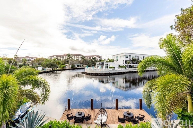 A serene waterfront scene with a dock and lounge chairs.