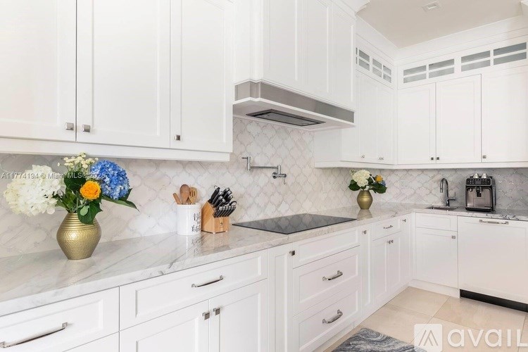 A kitchen with white cabinets and a marble countertop.