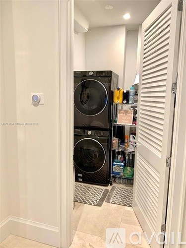 A washing machine is in the doorway of a white room.