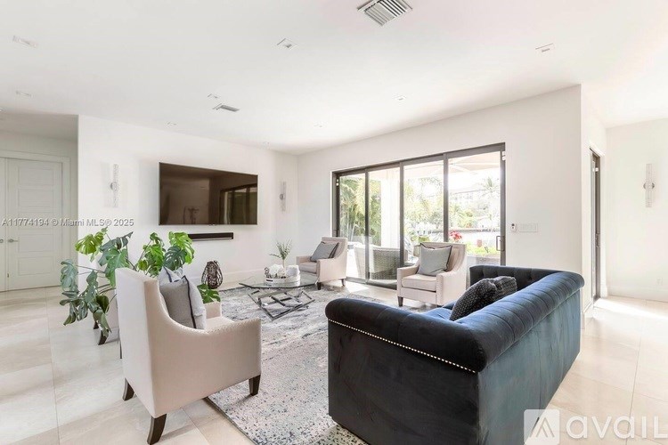 A living room with a black couch and a rug.