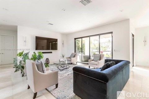 A living room with a black couch and a rug.