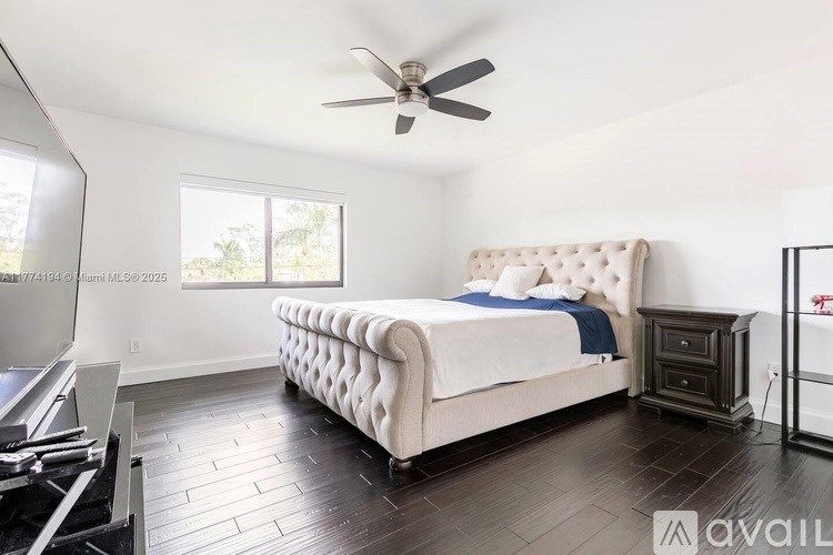 A bedroom with a large bed and a ceiling fan.