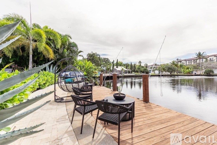 A wooden deck with chairs and a table overlooks a body of water.