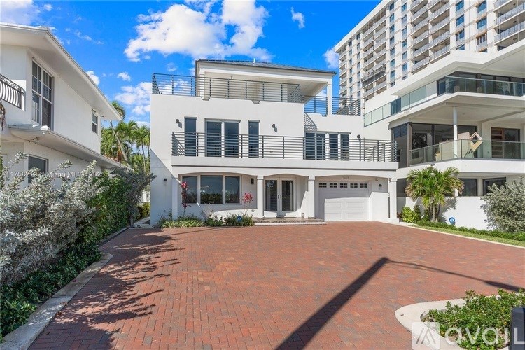 A modern white house with a red brick driveway in front.