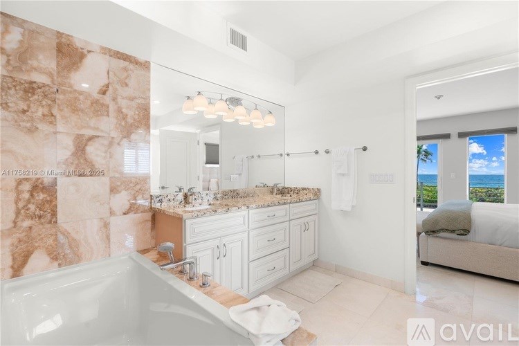A bathroom with a marble tile wall and a view of the ocean.
