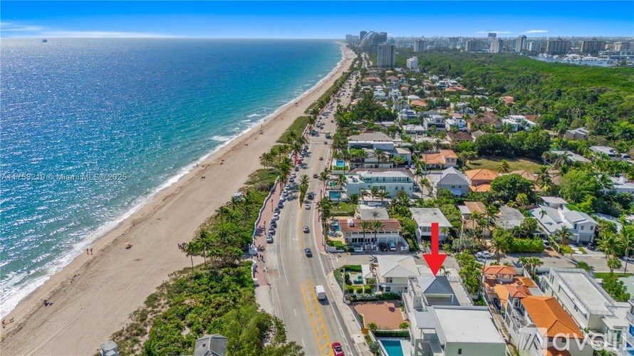 A beachfront street with a red arrow pointing to a house.