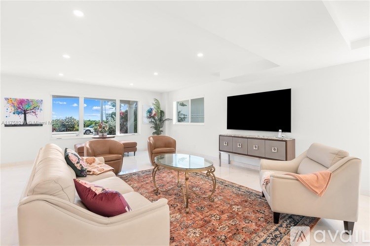 A living room with a sofa, chairs, and a television.
