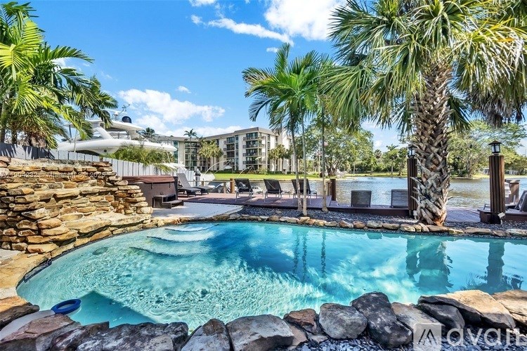 A pool surrounded by rocks and palm trees.