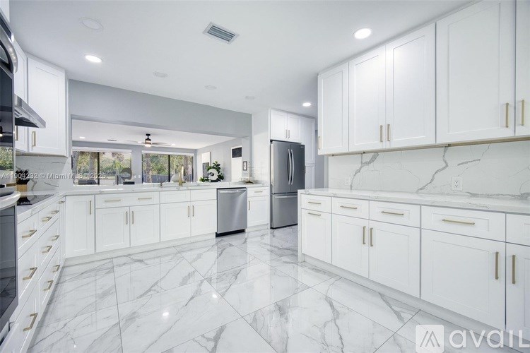 A modern kitchen with white cabinets and marble flooring.